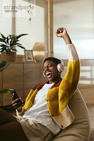 Fröhliche junge Frau  die zu Hause Musik hört und singt