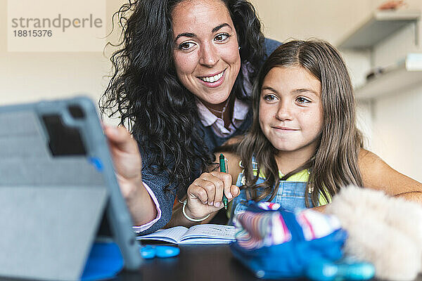 Mother homeschooling daughter with tablet PC at home
