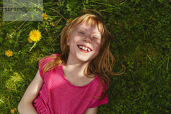 Glückliches erdbeerblondes Mädchen  das auf Gras liegt