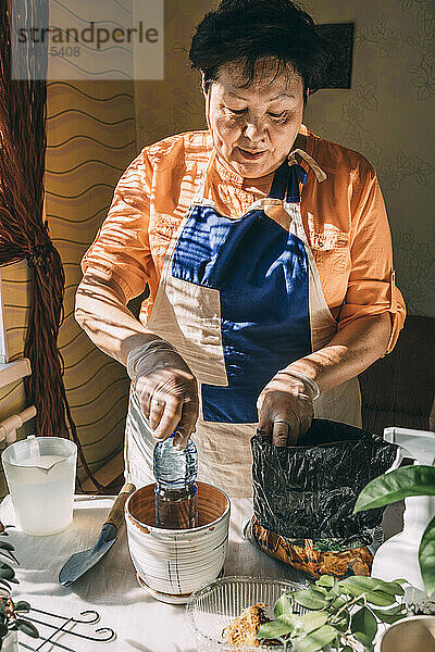 Ältere Frau bereitet sich auf das Pflanzen auf dem heimischen Tisch vor