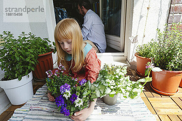 Blondes Mädchen hält Pflanze auf dem Balkon