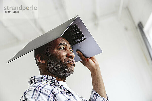 Bored businessman carrying laptop on head