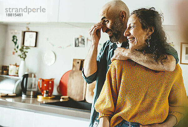 Happy man with arm around mature woman at home