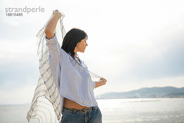 Reife Frau mit Schal am Strand