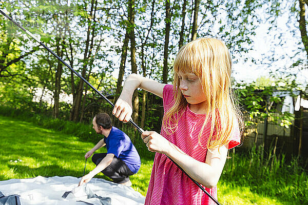 Mädchen hilft Vater  Zelt für Camping vorzubereiten