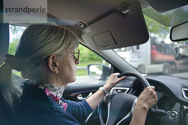 Ältere Frau mit Brille fährt Auto