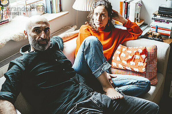 Multiracial couple sitting on sofa at home