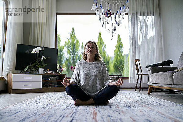 Ältere Frau praktiziert Meditation zu Hause