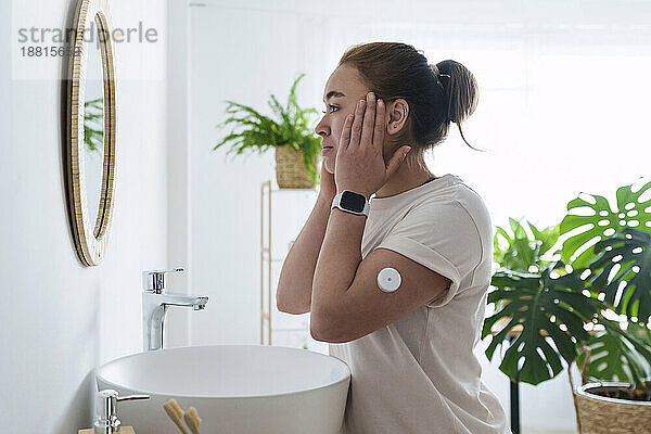 Woman with diabetes touching face in bathroom at home