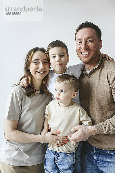 Glücklicher Vater und Mutter mit Söhnen vor weißem Hintergrund