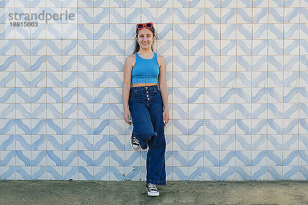 Mädchen mit Sonnenbrille lehnt an der Wand