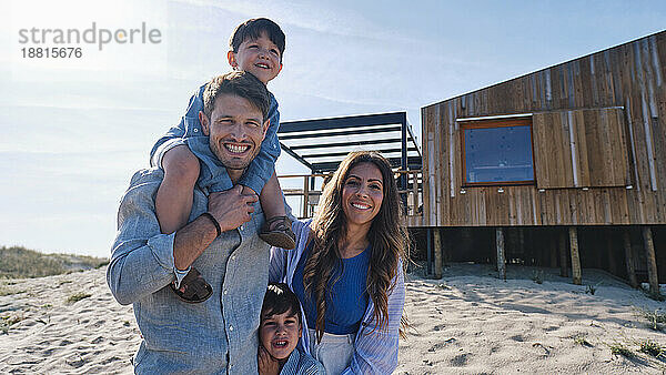 Glückliche Familie steht zusammen vor dem Strandhaus