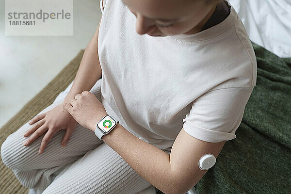 Woman with diabetes checking sugar levels on smart watch at home