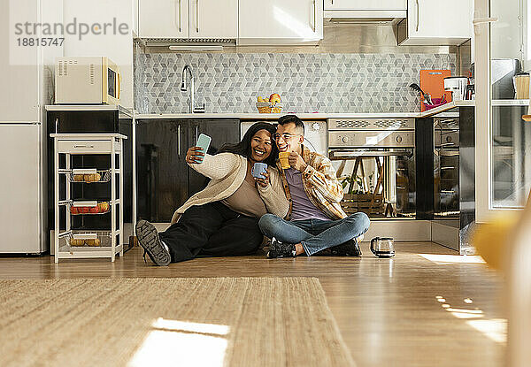 Glückliches Paar macht ein Selfie mit einer Kaffeetasse in der Küche