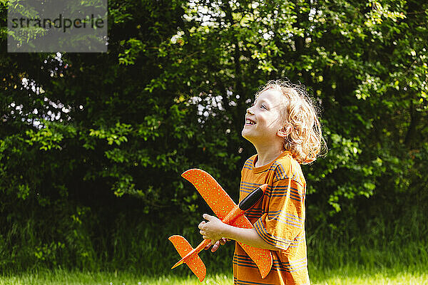 Smiling blond boy with airplane toy at park