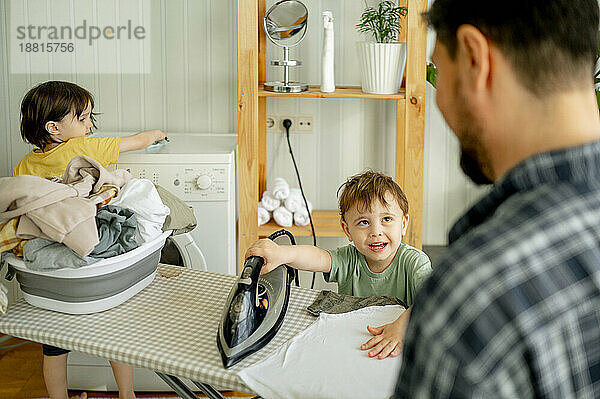 Father with son ironing clothes at home