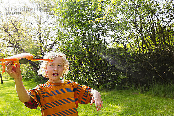 Happy blond boy playing with airplane toy