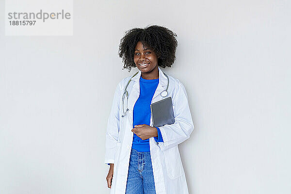 Junger Afro-Arzt mit Tablet-PC vor weißem Hintergrund