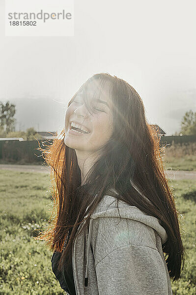 Happy teenage girl in field at sunny day