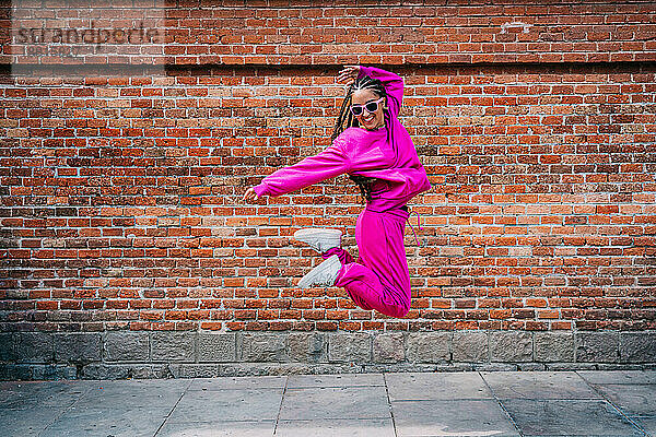 Fröhliche Frau springt vor einer Mauer