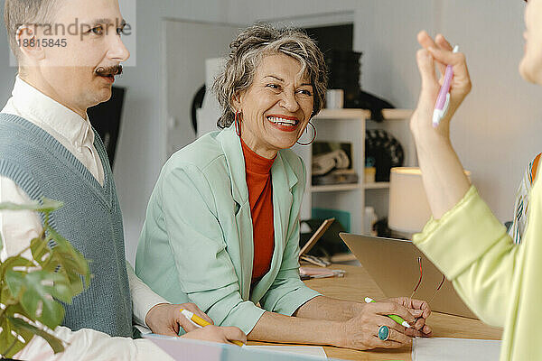 Woman in bright clothes talks with colleagues  having fun at the studio