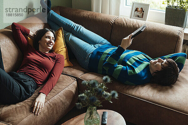 Smiling lesbian couple spending leisure time lying down on sofa at home