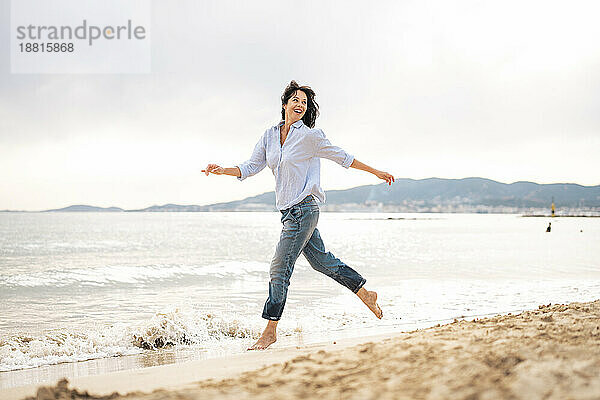 Glückliche reife Frau  die am Strand am Meer läuft