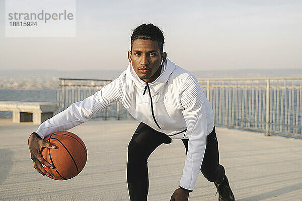 Selbstbewusster Athlet dribbelt mit Basketball am Pier