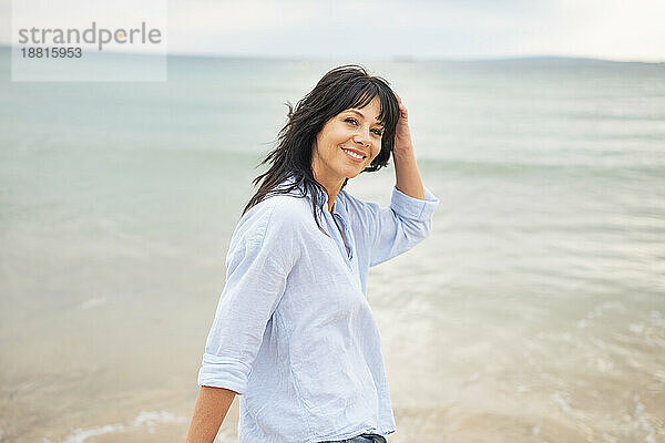 Smiling woman with hand in hair at beach