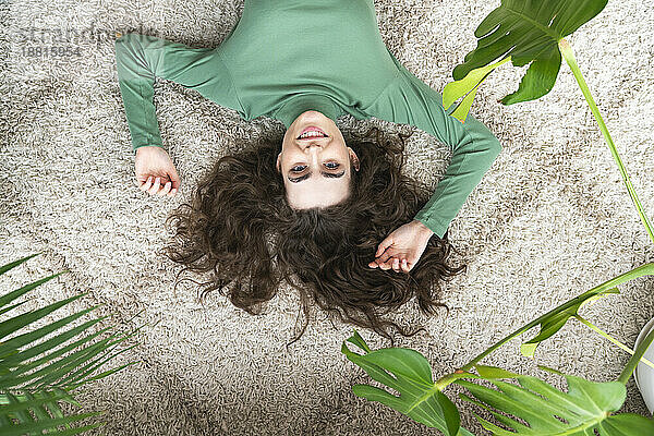 Smiling young woman lying on rug at home