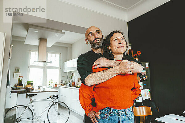 Mann umarmt Frau  die zu Hause nachdenkt