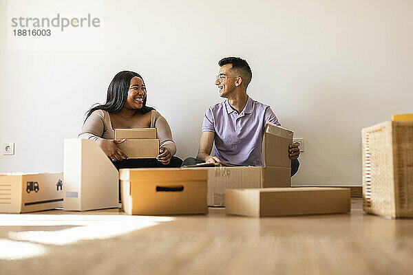 Glückliches Paar packt Kartons im neuen Zuhause aus