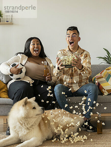 Excited couple celebrating on sofa by dog at home
