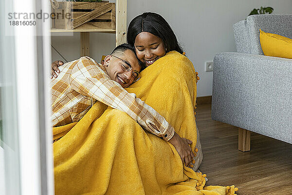 Man embracing woman covered with yellow shawl at home