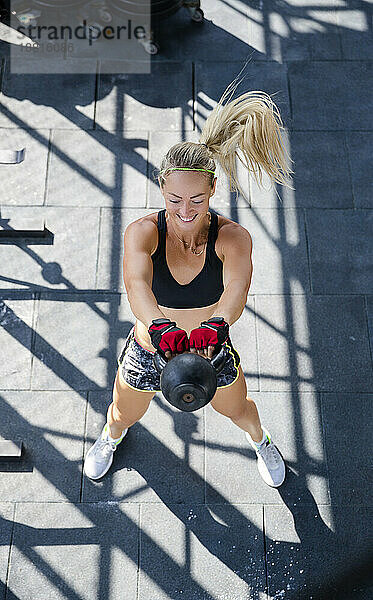 Frau trainiert mit Kettlebell im Fitnessstudio auf dem Dach