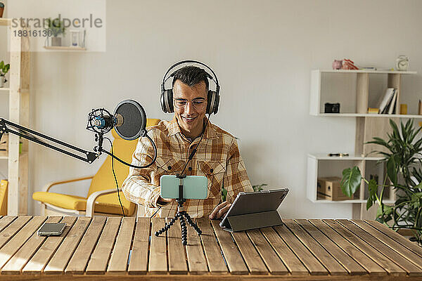 Mann Podcasting vor Smartphone und Tablet-PC am Schreibtisch