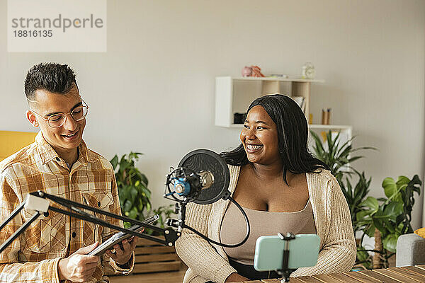 Lächelndes Paar beim Podcasting zu Hause