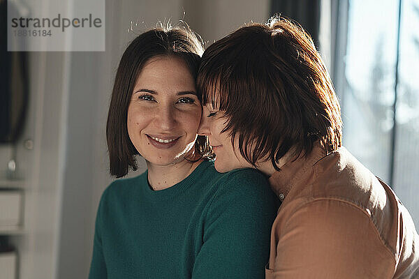 Smiling woman with romantic lesbian friend at home
