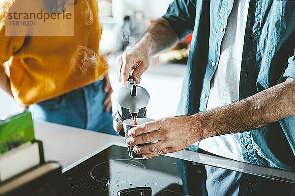 Mann gießt zu Hause Kaffee in Tasse