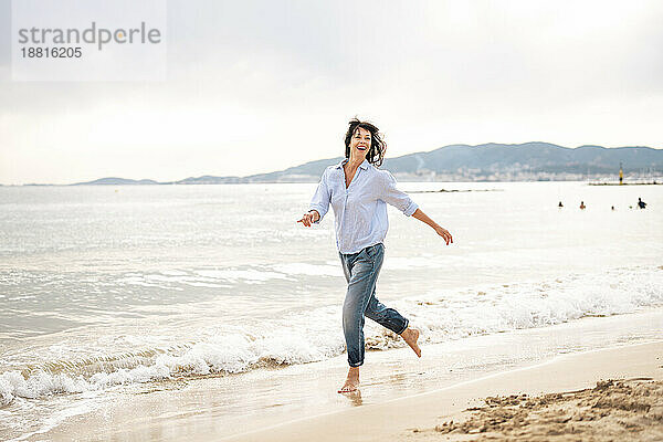 Sorglose Frau läuft in Ufernähe am Strand