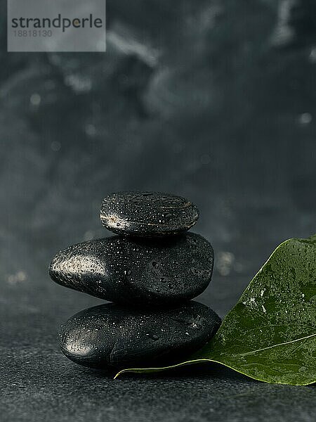 Stacked Massage Steine mit Blättern auf einem dunklen Stein Tisch  Spa Hintergrund