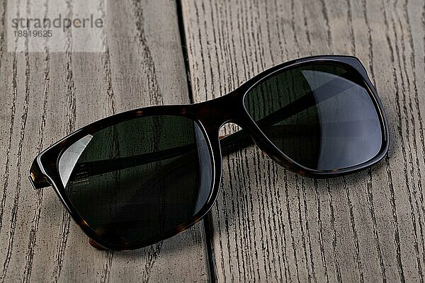 Schwarze Sonnenbrille auf einem hölzernen Hintergrund