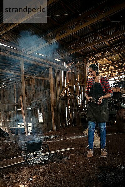 Die junge Frau in Uniform  die in einer Fabrik arbeitet und für alle mit Feuer auf dem Boden kocht
