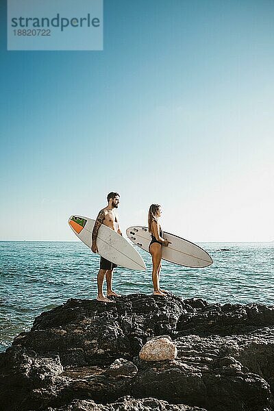 Junger Mann Frau mit Surfbrett Stein am Meer