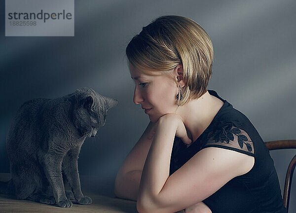 Portrait einer Frau mit ihrer Russisch Blau Rassekatze die ihre Zuneigung zeigt