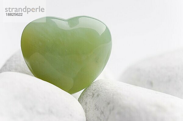 grünes quarz mineral herz als symbol der liebe auf weißen steinen