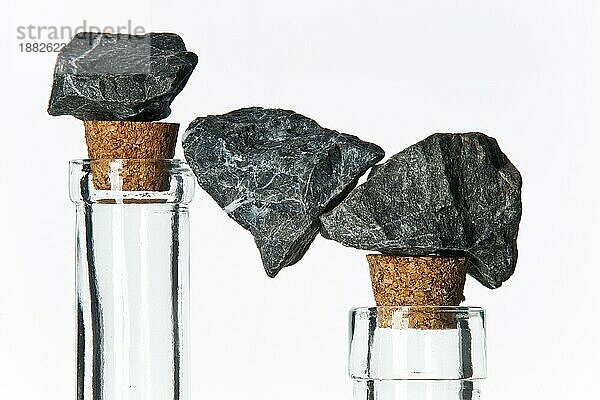 steine in balance auf glasflaschen mit korken