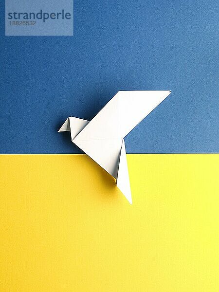 Friedenssymbol mit einer Origami Taube auf blauem und gelbem Papier als ukrainische Flagge