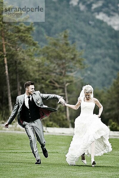 Braut und Bräutigam laufen auf dem grünen Gras
