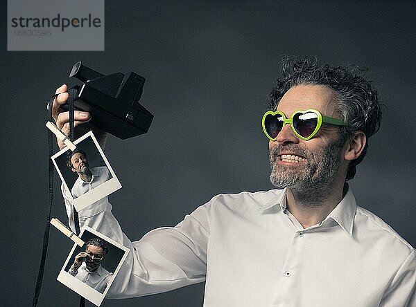 Herzförmige Brille trägt Mann mit Sofortbildkamera nehmen selfie  retro Farbe getönt